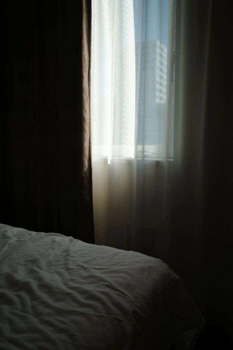 Crumpled white duvet on a bed in a dimly lit bedroom